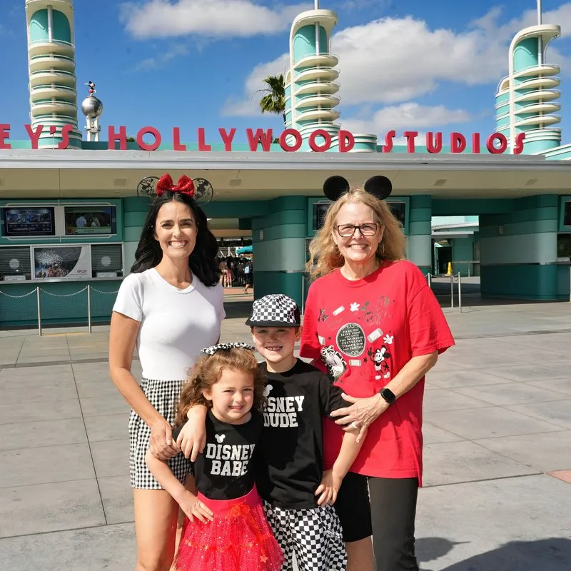 Two adults and two kids in Disney outfits outside the entrance to Disney’s Hollywood Studios