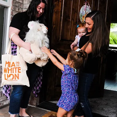 A family being handed a Mia and the White Lion plush toy and tote bag
