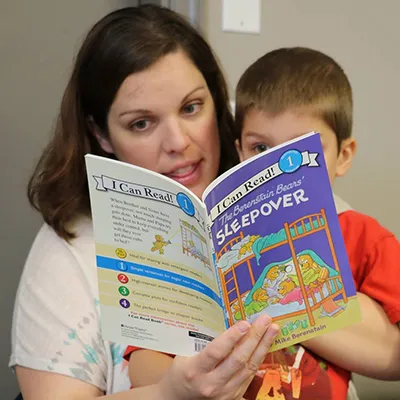 A parent reading an I Can Read! Berenstain Bears book with her son