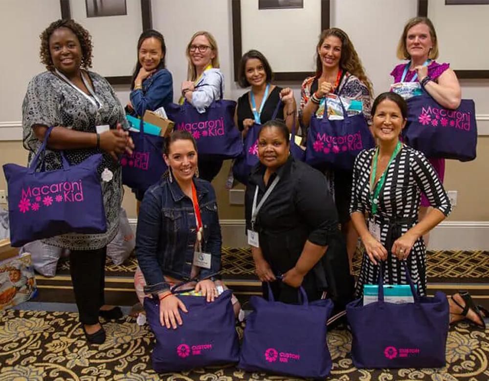 Publishers holding Macaroni KID tote bags at the annual conference
